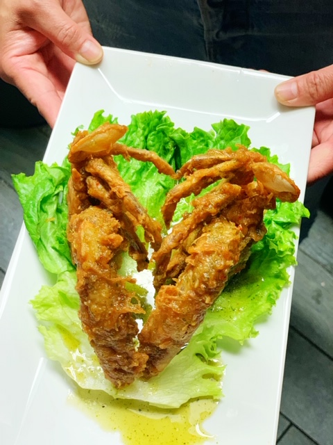 A server holding a plate of soft-shell crab.